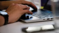 Hands typing on a laptop